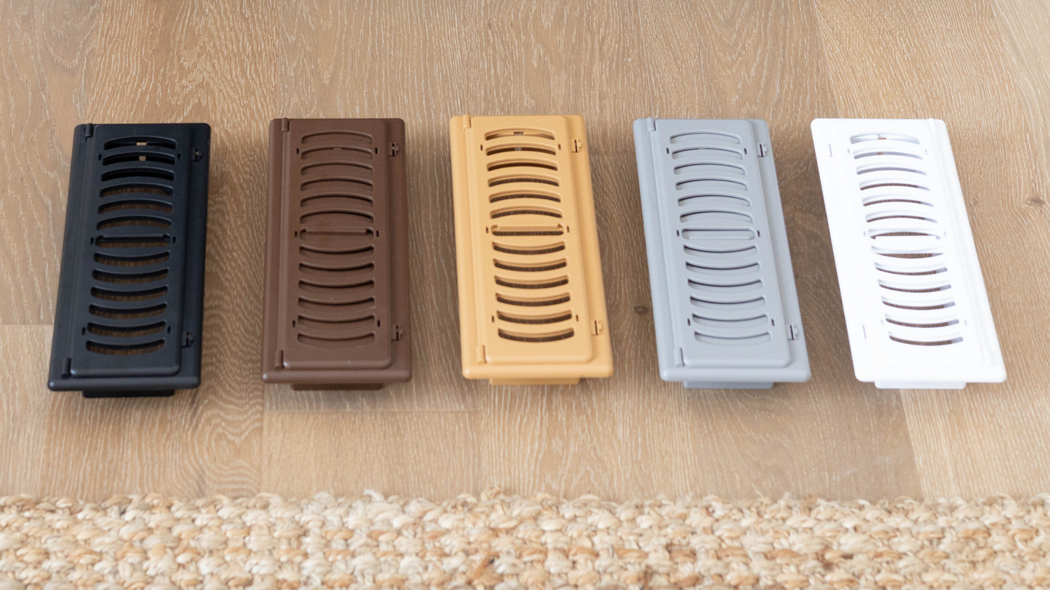 Five childproof vent covers lined up showing different colours: black, brown, tan, grey, white